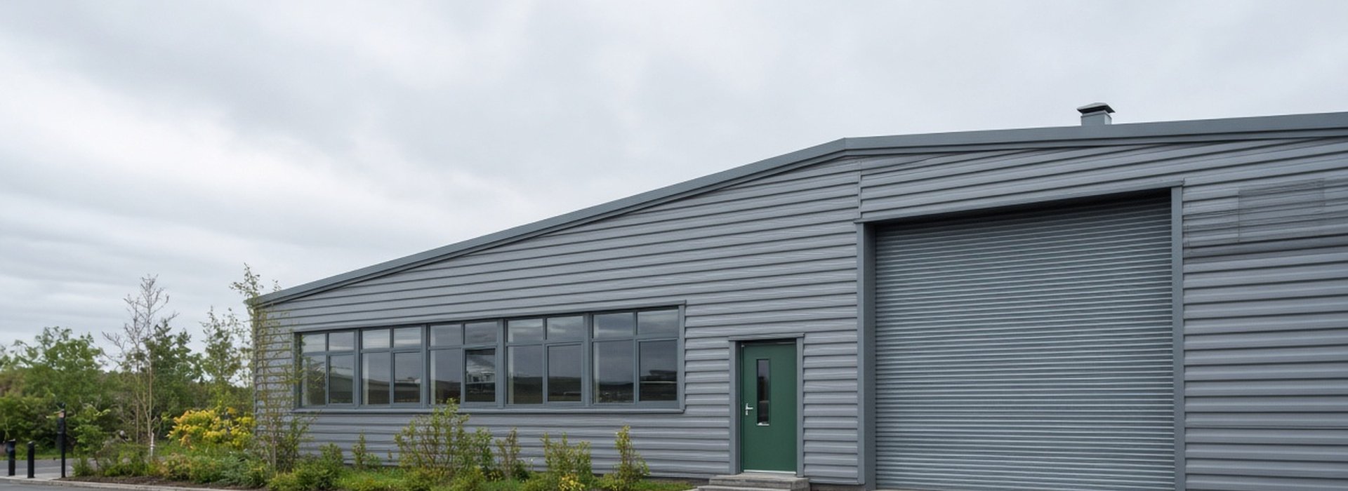 Commercial industrial unit with a roller shutter door, steel fire exit door and windows